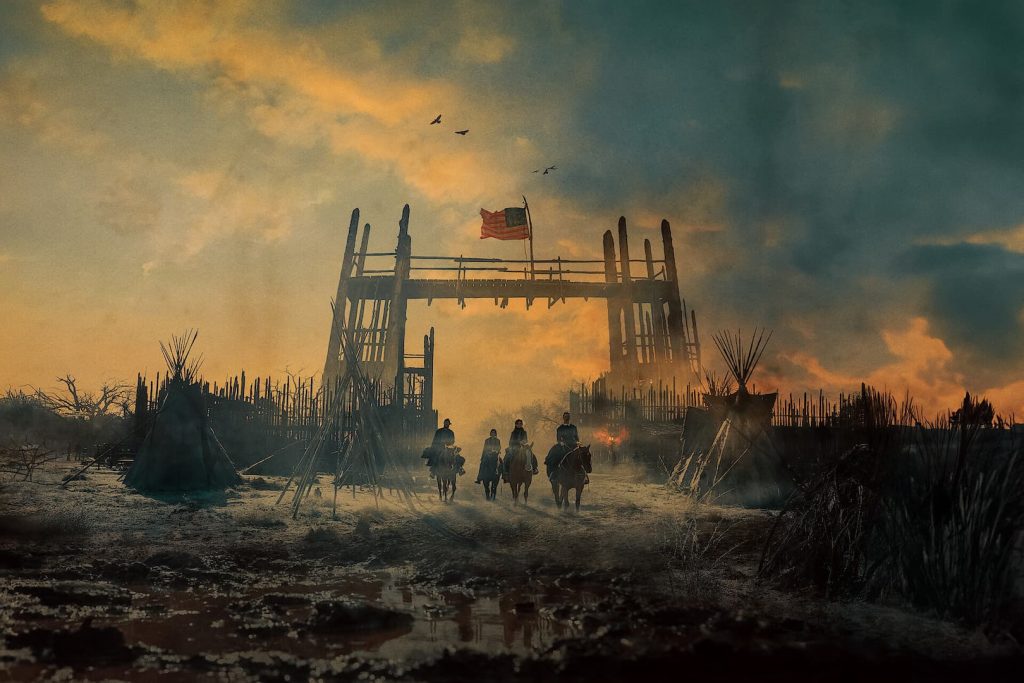 Isaac, Sara, Devin et Deux Lunes à cheval traversant un camp en ruines sous un ciel embrasé dans la série À l’Aube de l’Amérique.